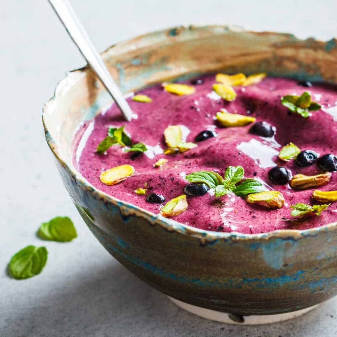 blueberry-smoothie-bowl-with-pistachios-mint-white-background
